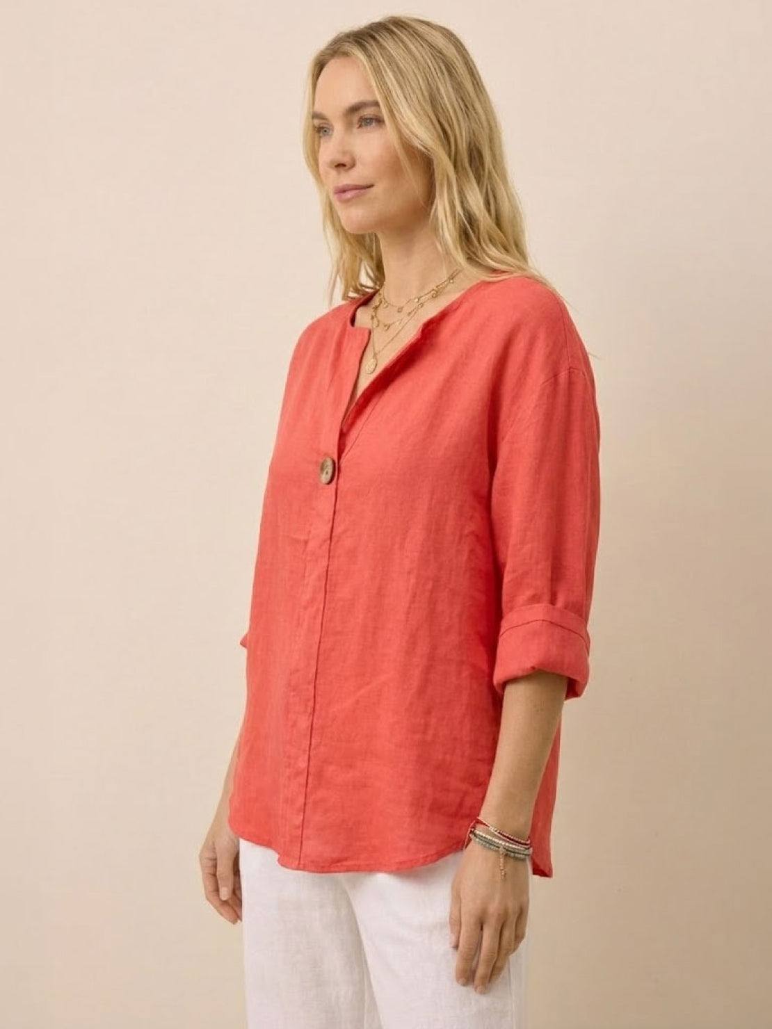 woman wearing coral pure linen age-defying button detail shirt with rolled sleeves and white pants