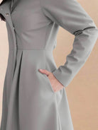 Woman wearing water-repellent A-line hooded raincoat with belt in outdoor setting