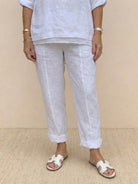 White asymmetrical two-piece trouser set with rolled-up sleeves and slightly tapered pants in breathable linen-like fabric.