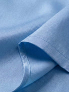 Close-up of light blue breathable fabric from asymmetrical two-piece trouser set with smooth texture and fine stitching.