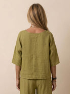 Back view of woman wearing olive green short-sleeved pullover and wide trouser matching set