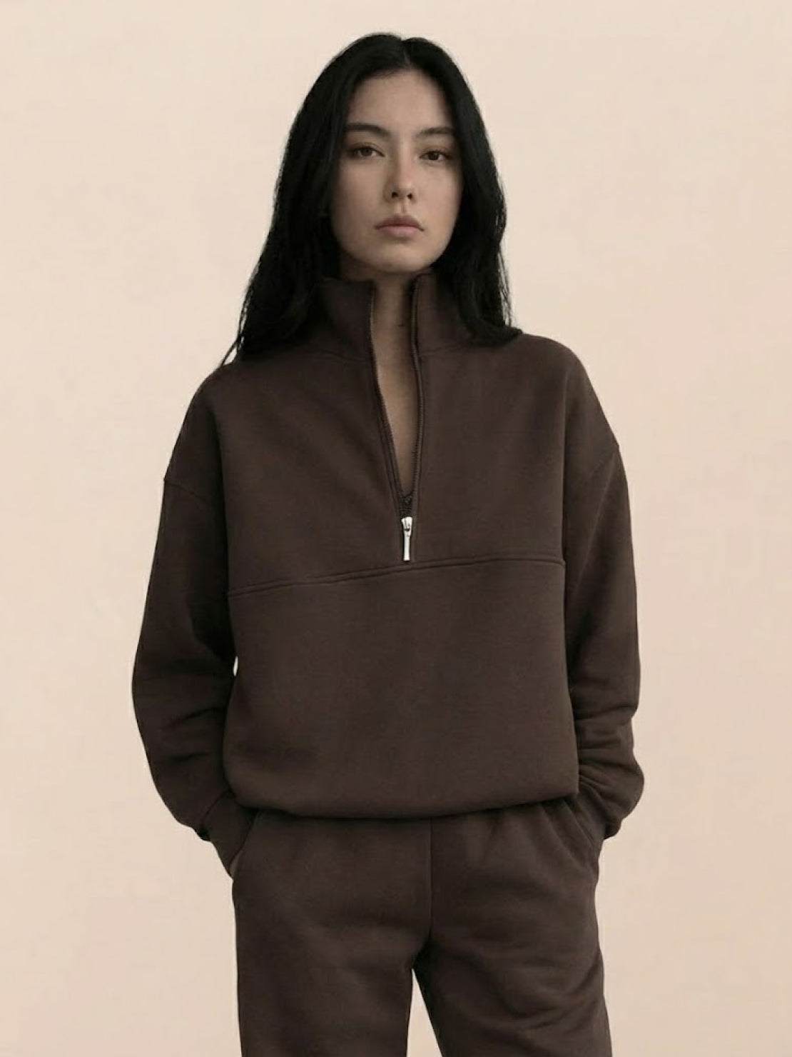 Woman wearing a cotton-blended two-piece tracksuit with high collar and deep zipper, styled for athleisure comfort and casual confidence