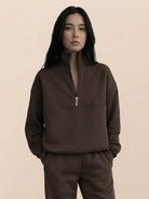 Woman wearing a cotton-blended two-piece tracksuit with high collar and deep zipper, styled for athleisure comfort and casual confidence