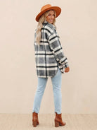 Woman wearing comfy flannel classic button-down shirt with plaid pattern, light jeans, brown boots, and hat