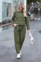 Woman wearing olive green cotton-linen monochrome longline top and wide-leg pants set walking outdoors with white sneakers and sunglasses