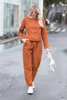 Woman wearing rust-colored cotton-linen monochrome capsule set with longline top and wide-leg pants, styled for casual wear.
