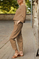 Woman wearing relaxed brown cotton-linen monochrome capsule outfit with longline top and wide-leg pants outdoors