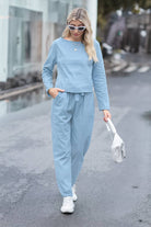 Woman wearing blue cotton-linen monochrome capsule outfit with long sleeve top and wide-leg pants walking outdoors