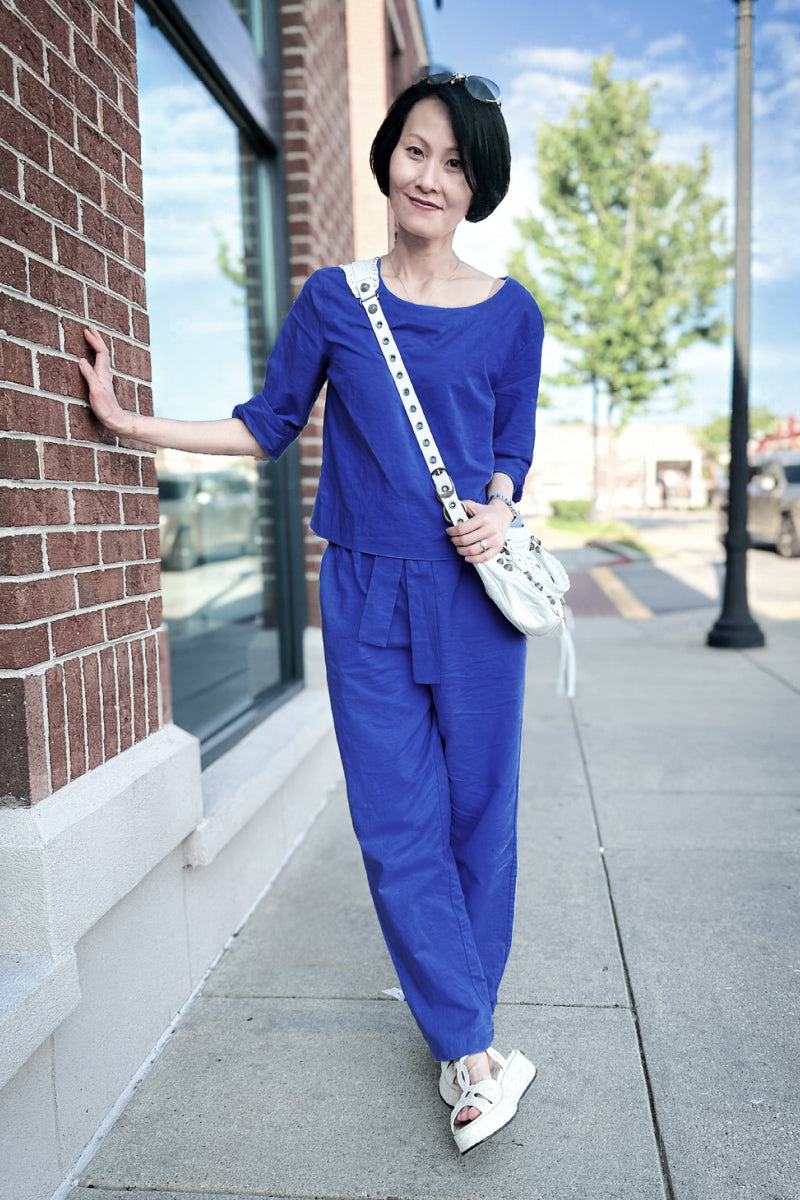 Woman wearing relaxed cotton-linen monochrome capsule longline top and wide-leg pants in blue on city sidewalk