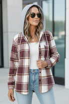 Woman wearing a Highland Plaid Shacket with burgundy and white plaid pattern, gray hood, sunglasses, white top, and light blue jeans outdoors