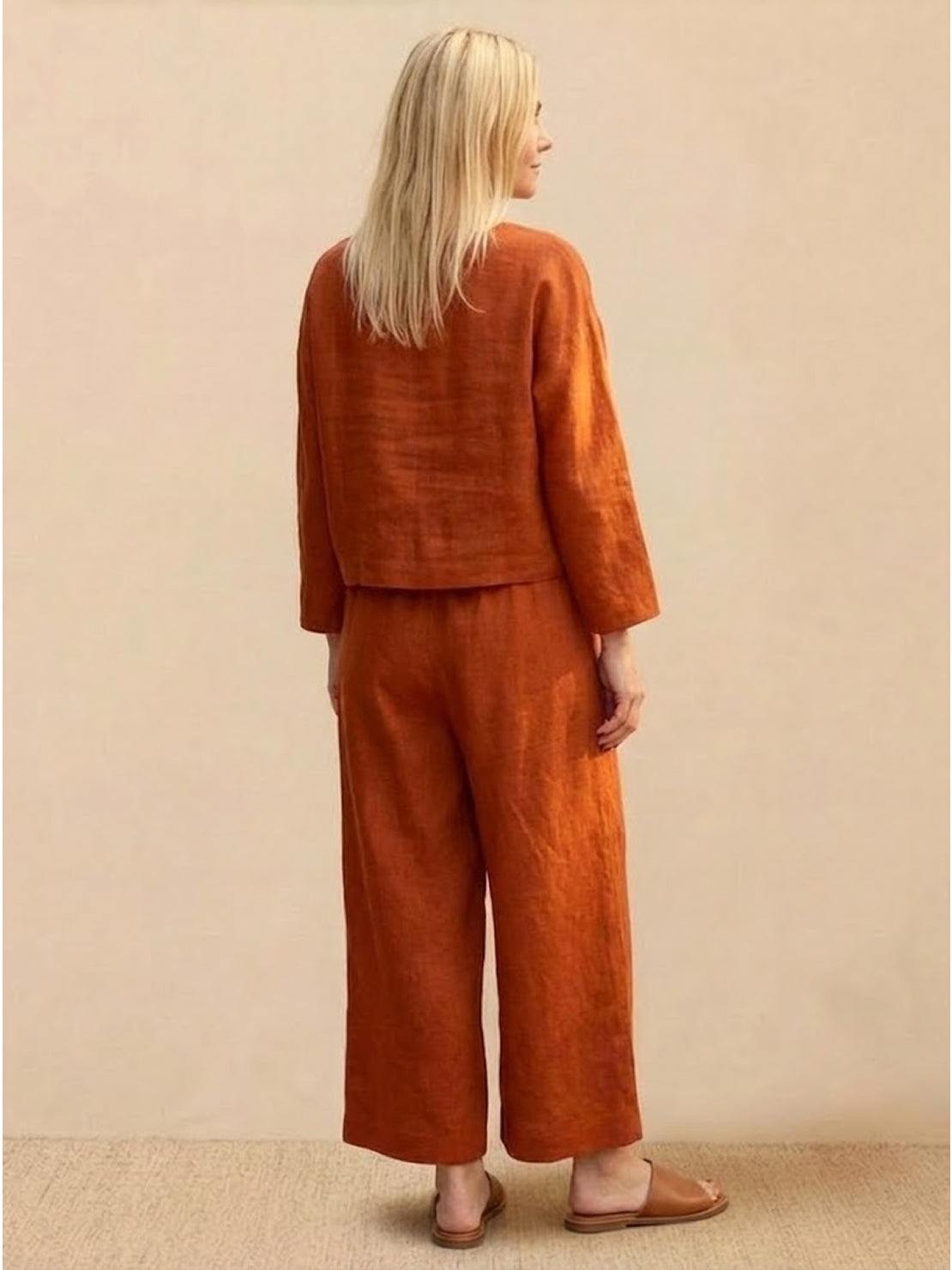 Woman wearing burnt orange loose solid color two-piece set with long sleeves and wide-leg pants, back view