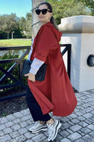 Woman wearing oversized red water resistant windbreaker jacket with hood and longline design outdoors