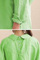 Close-up of oversized linen shirt in light green with rolled sleeves and back button detailing