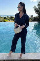 Woman wearing oversized 100% cotton black shirt and wide-leg pants co-ord set by poolside