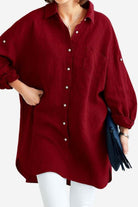 Red oversized linen shirt with long sleeves and front pocket styled with white pants and a black clutch bag