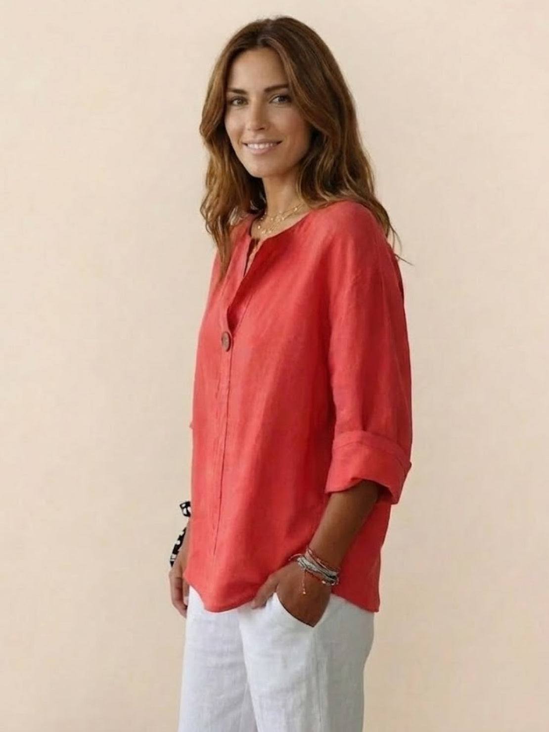 Woman wearing coral pure linen age-defying shirt with button detail and white pants