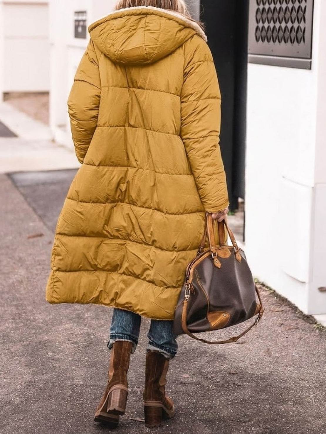 woman wearing mustard sherpa-lined hooded teddy coat with puffer construction walking outdoors carrying brown leather handbag