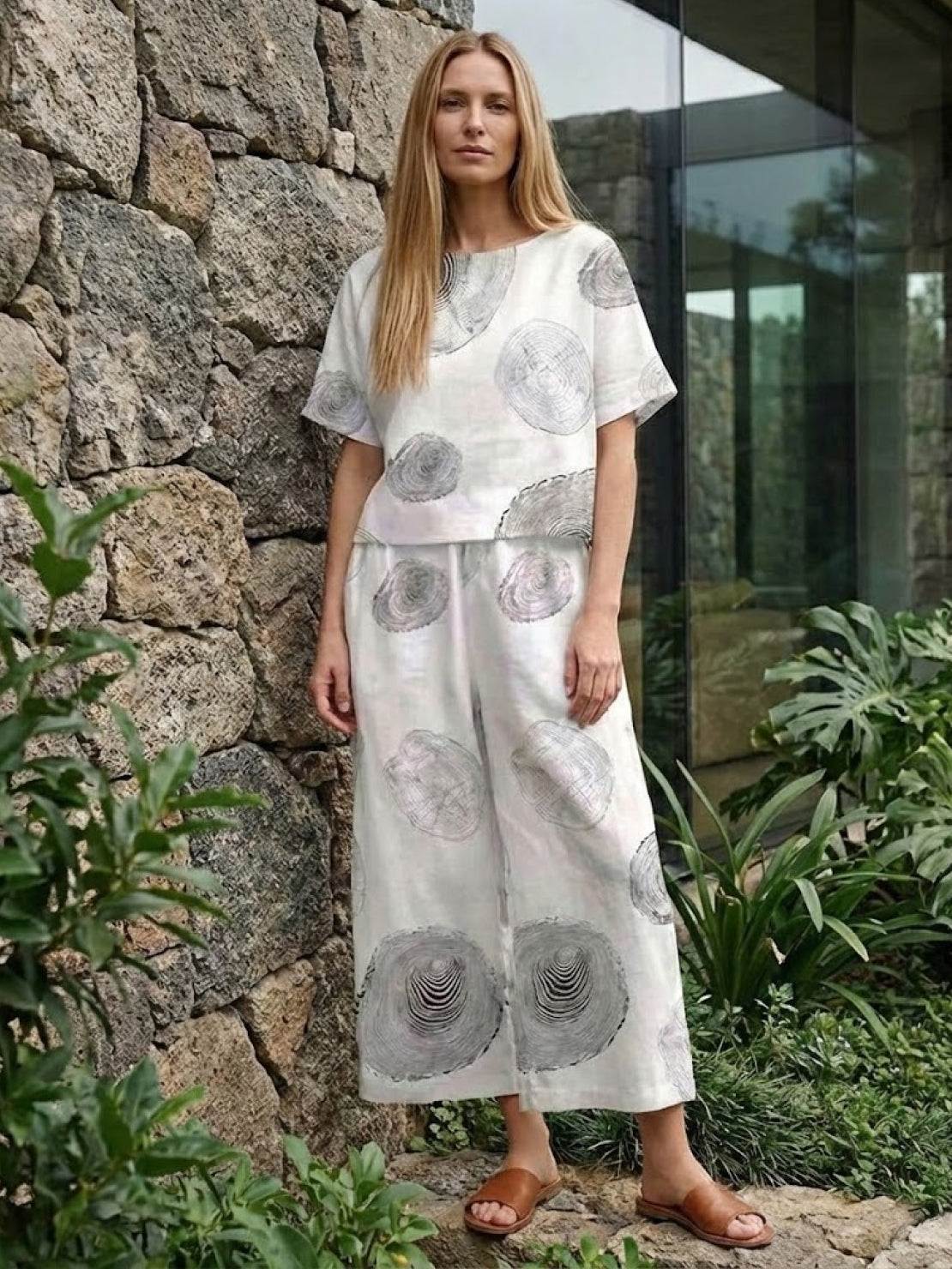 Woman wearing loose fit co-ord set with wide-leg trousers and short-sleeve top in soft floral print outdoors