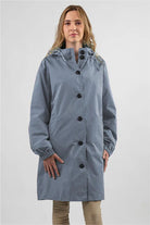 Woman wearing oversized blue Rain Couture Windbreaker water-resistant jacket with hood and button closure