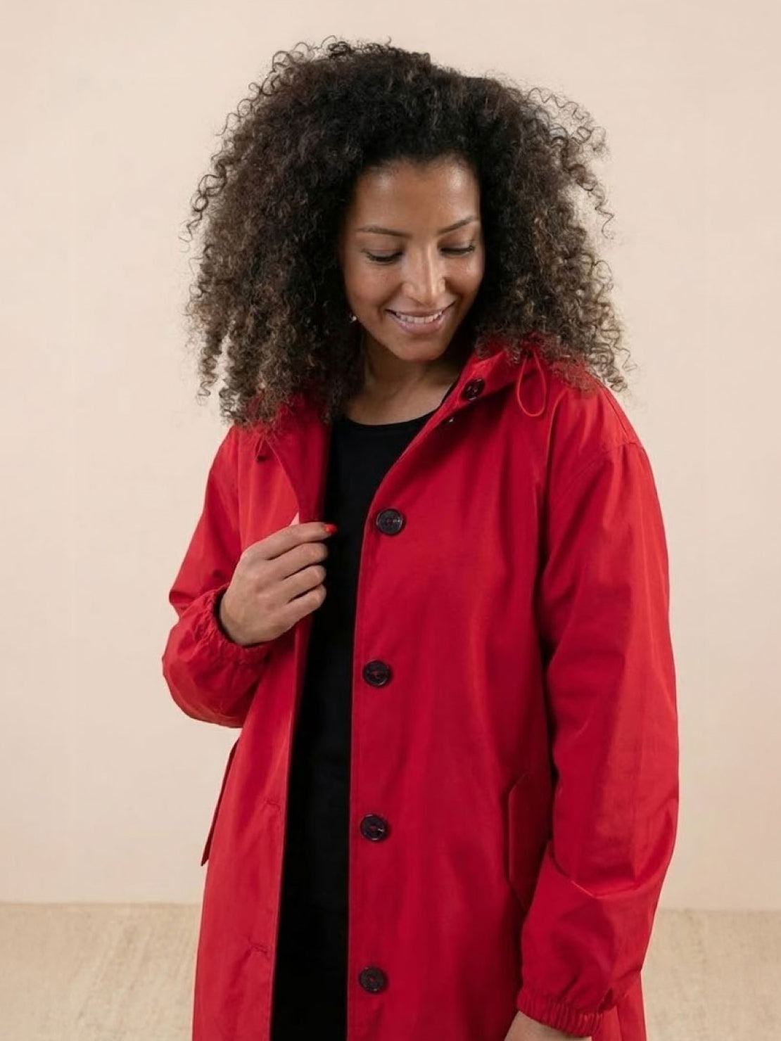 Woman wearing red oversized Rain Couture Windbreaker water-resistant jacket with buttons and hood