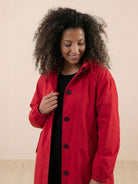Woman wearing red oversized Rain Couture Windbreaker water-resistant jacket with buttons and hood