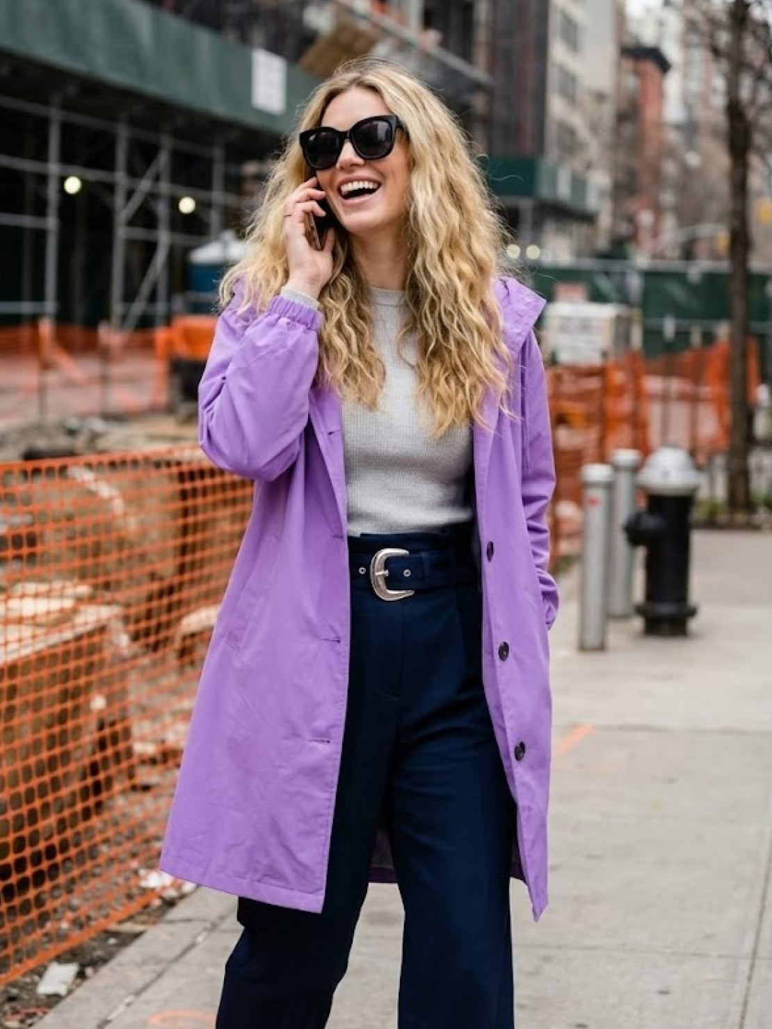 Woman wearing oversized purple Rain Couture Windbreaker with sunglasses outdoors in city.