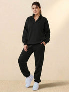 Woman wearing black ultra-soft and comfy co-ord tracksuit set with white sneakers against neutral background