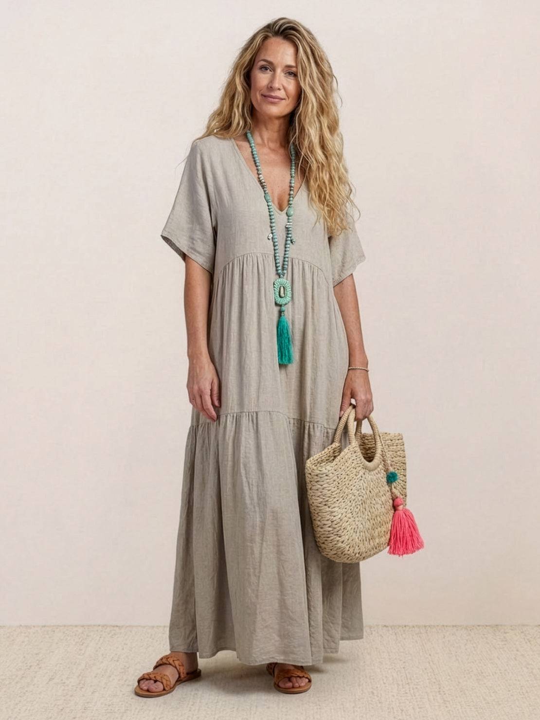 Woman wearing a khaki V-neck two-tiered maxi swing dress with flowy tiers and loose sleeves