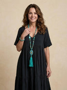 Woman wearing a V-neck two-tiered maxi swing dress with irregular hemline and flowy sleeves in a casual outdoor setting